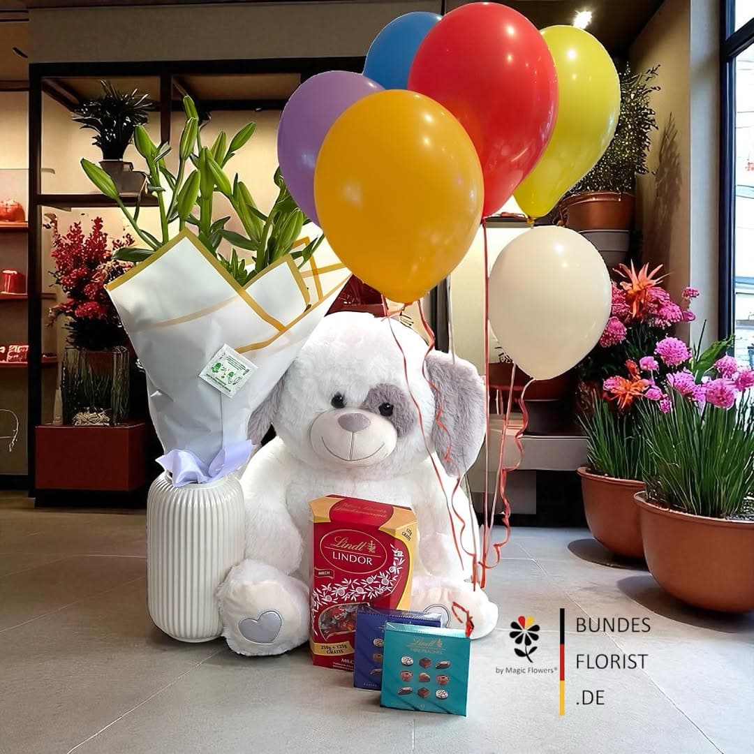 Zur Einschulung — ein Strauß frischer Lilien mit Pralinen, Ballons und kuscheligem Teddy.